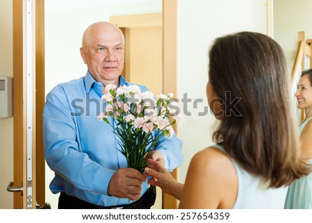 Senior man came to mature woman with flowers at home door