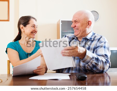 Happy senior couple with financial documents at home