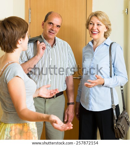 Young woman meeting smiling mature friends at the door