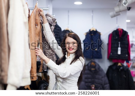 Young woman choosing jacket at clothing store
