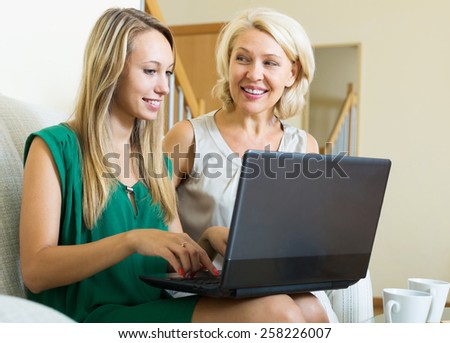 Smiling daughter teaching mother to computer literacy