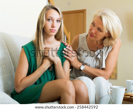 Mature mother comforting sad daughter indoor