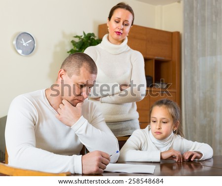 Poor family counting money to pay bills at the table. Focus on man