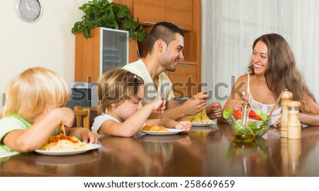 happy family of four  eating  pasta at home together