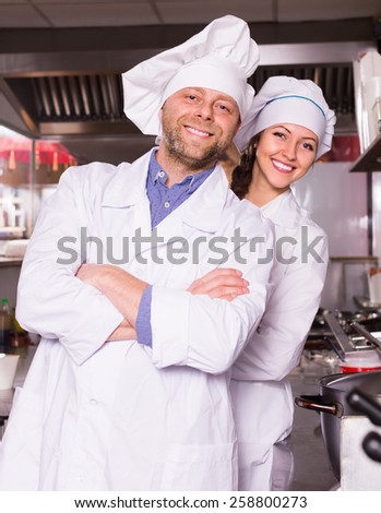Portrait of smiling chef with young beautiful female helper at restaurantÃ?ÃÂ¢??s kitchen