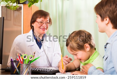 Friendly smiling elderly pediatrician doctor examining child at clinic office
