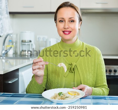 Smiling female sitting at table with fish and rice in plate