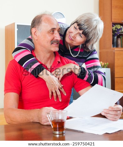 Loving mature  couple with financial documents at table in home interior