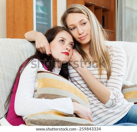 crying woman has problem, other woman  consoling her at sofa in home