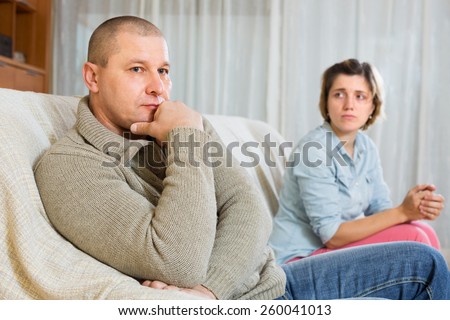 Couple quarrel at home. Sad ordinary man against unhappy woman