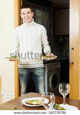 Smiling man serving cooked fish on family table at home