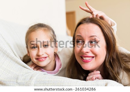 Laughing and hugging mom and little daughter indoors
