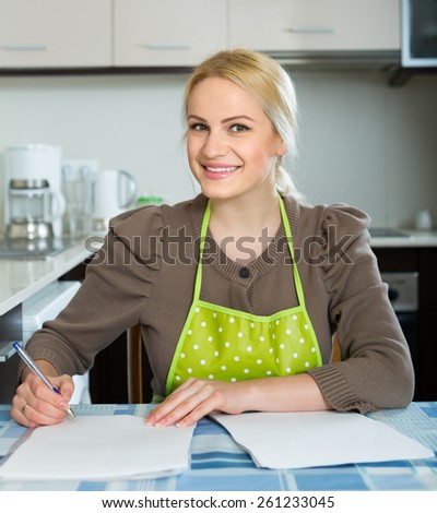 Happy woman at kitchen signing contractual agreement for renting new flat
