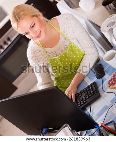 blond female freelancer with PC, tea and sandwich at kitchen table