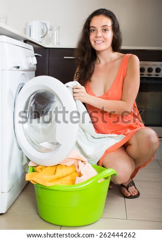 Home laundry. Smiling young woman using washing machine at home