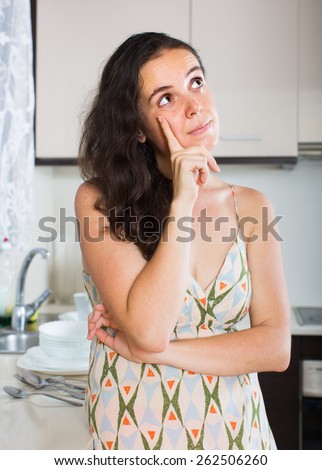 Confused housewife thinking what to prepare for dinner at kitchen