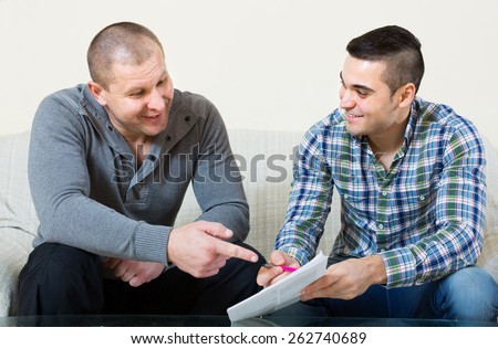 Smiling male agent explaining to client terms of life insurance at home