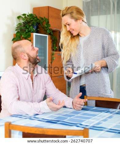 Husband and long-haired wife reading insurance contract at home