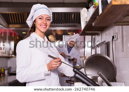 Two happy smiling cooks working together at kitchen in take-away restaurant