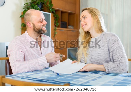 Happy smiling husband and wife signing a contract and buying apartment