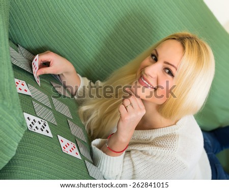 Young woman liying on a couch playing solitaire card game
