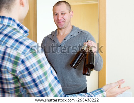 Cheerful adult man visiting friend and bringing beer