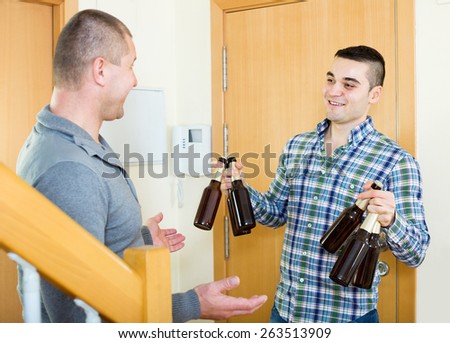 Smiling adult man visiting friend and bringing beverage