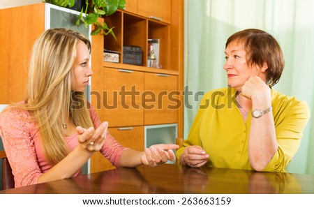 Mature mother with  adult daughter having serious conversation in home