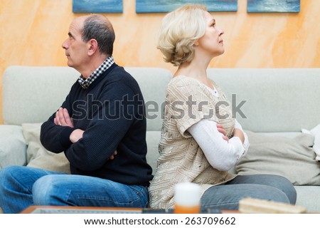 Family quarrel. Upset mature female against elderly man at home. Focus on woman