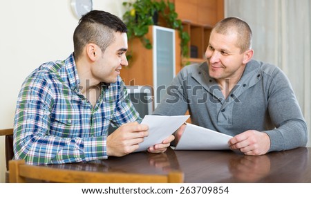 Smiling male agent consulting client about terms of contract at home