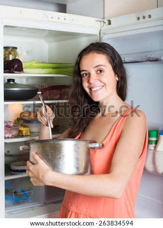 hungry woman with pan near fridge  at home