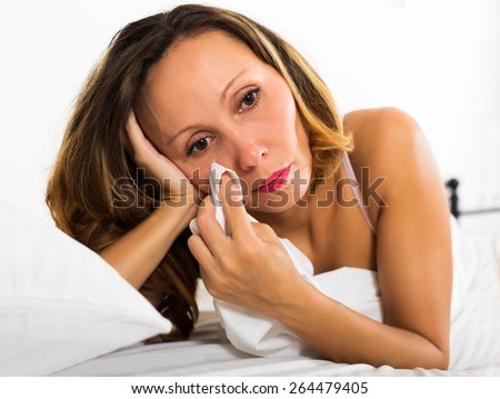 Portrait of thoughtful sad female with downcast eyes in bedroom