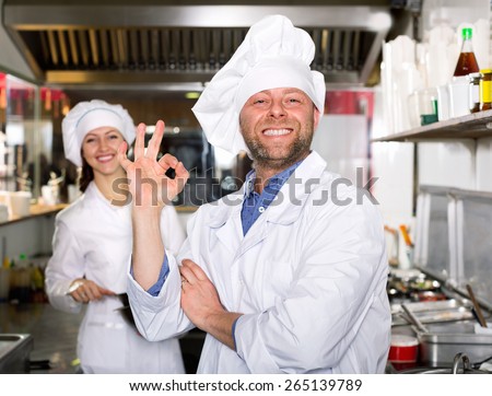 Cheerful professional chef and cook  working  in restaurant kitchen