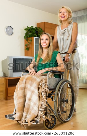 Smiling elderly mother with handicapped girl in the living room. Focus on girl