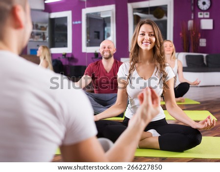 Smiling people studying new position at yoga school