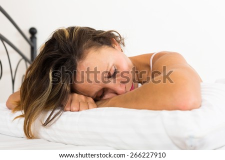 Upset middle-aged woman laying in bed with dropped eyes