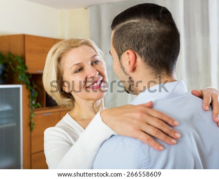 Adult son asking smiling mother to dance at home