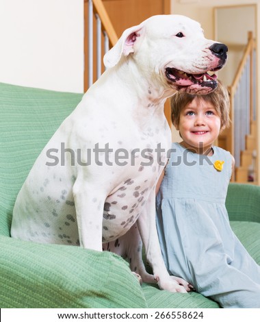 Happy smiling little girl with big white dog at home. Focus on dog