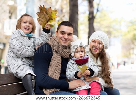 Mom, dad and two children posing outdoor at fall day