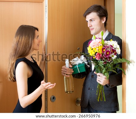Smiling man giving gifts to beautifull woman at home door