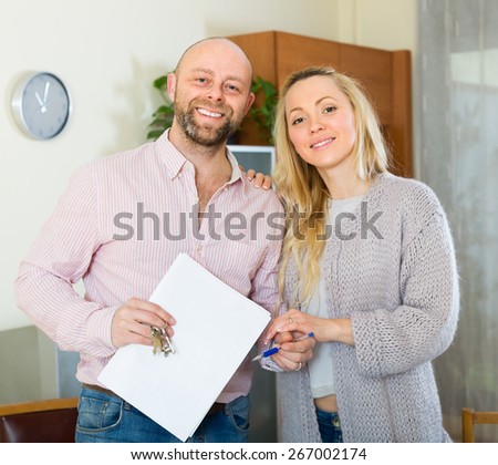 Happy smiling young married couple with contract for buying apartment and keys
