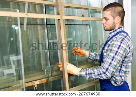 Workman cutting glass for windows at workshop