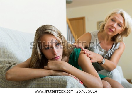 Mature woman comforting sad daughter at home