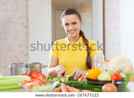 Portrait of  happy woman cooking  vegetarian salad at domestic kitchen