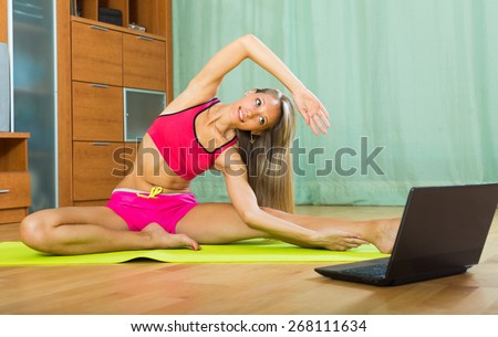 Positive happy smiling girl doing yoga with laptop at home