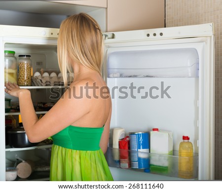 woman looking for something in refrigerator  at home kitchen