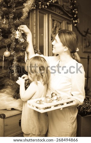Vintage photo of young mother and daughter celebrating Christmas in living room
