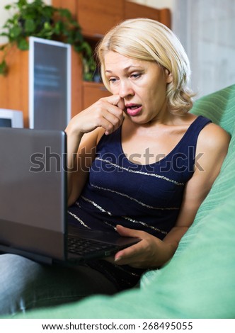 Crying mature blonde lady receiving bad news in internet