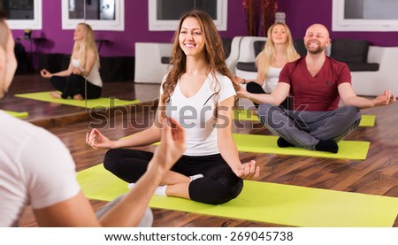 Happy adult people studying new position at yoga school