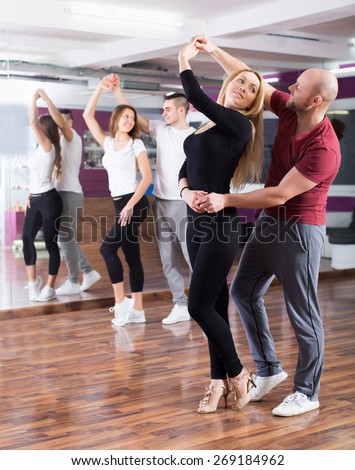 Positive couples enjoying of partner dance and smiling indoor
